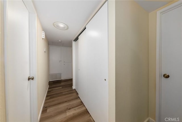 corridor featuring light wood finished floors, visible vents, and baseboards