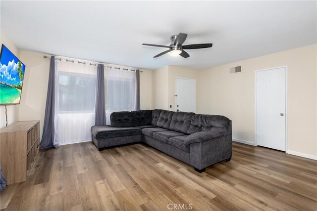 living room featuring light wood finished floors, a ceiling fan, and baseboards
