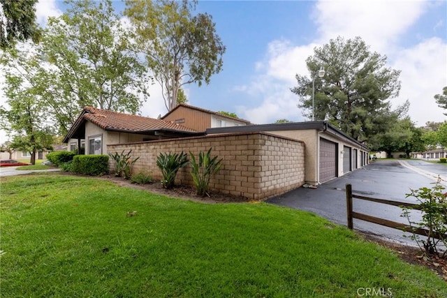 view of side of property with fence, driveway, stucco siding, and a lawn