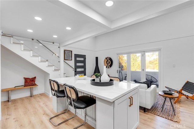 kitchen featuring white cabinets, light wood finished floors, light countertops, a kitchen breakfast bar, and recessed lighting