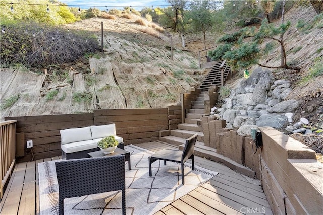 wooden deck with an outdoor hangout area, fence, and stairway