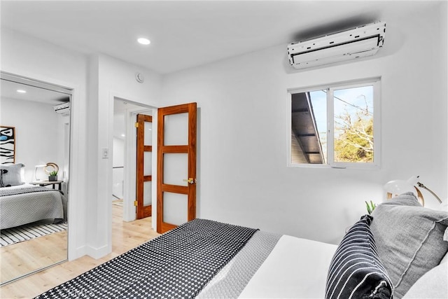 bedroom with recessed lighting, light wood-style flooring, and a wall mounted air conditioner