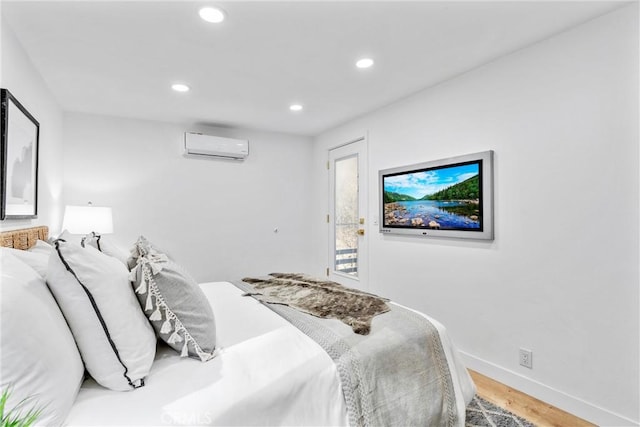 bedroom featuring recessed lighting, a wall mounted air conditioner, baseboards, and wood finished floors