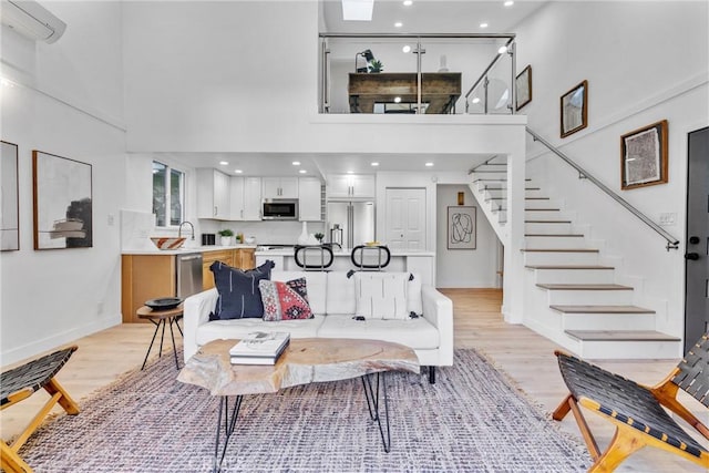 living room with baseboards, a high ceiling, light wood finished floors, and stairs