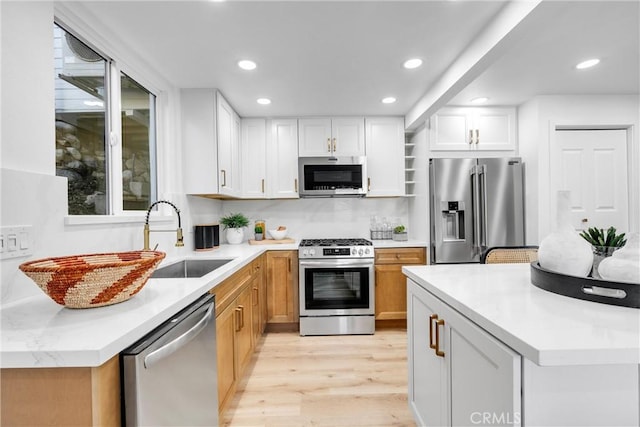 kitchen with light wood-style floors, recessed lighting, white cabinetry, a sink, and stainless steel appliances