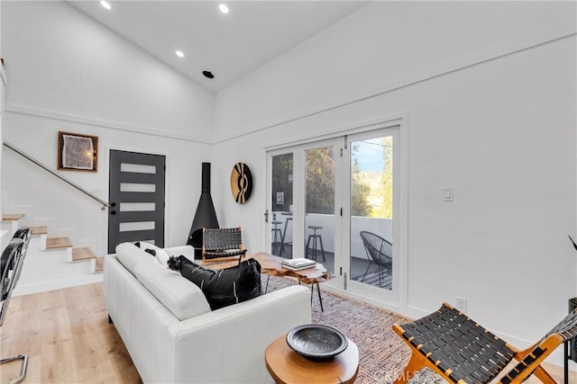 living area with stairway, high vaulted ceiling, baseboards, light wood-style floors, and recessed lighting