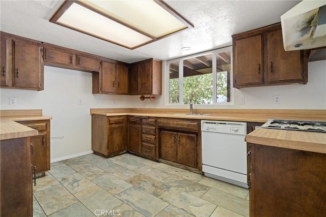 kitchen with a textured ceiling, white dishwasher, a sink, baseboards, and extractor fan