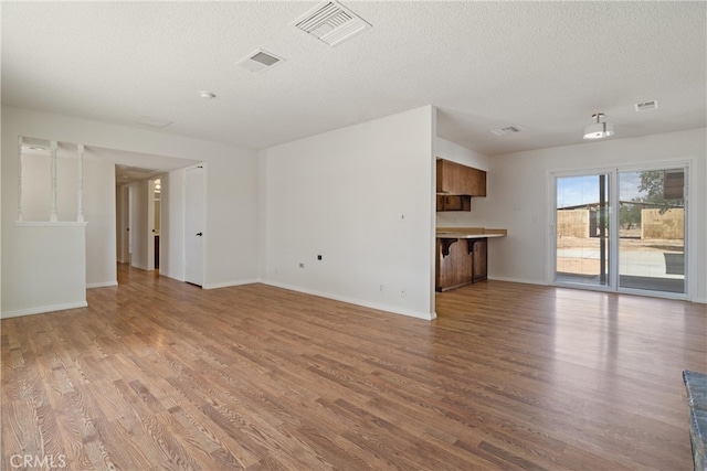unfurnished living room with visible vents, light wood-style floors, and baseboards