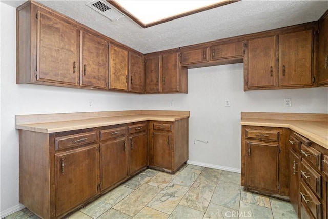 kitchen featuring light countertops, baseboards, and visible vents