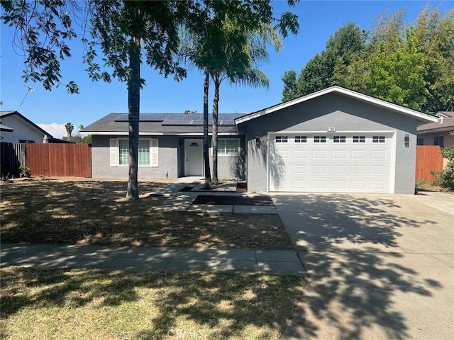 ranch-style house featuring stucco siding, fence, and roof mounted solar panels