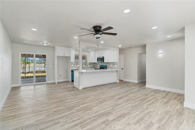 unfurnished living room featuring recessed lighting, baseboards, and light wood-style flooring