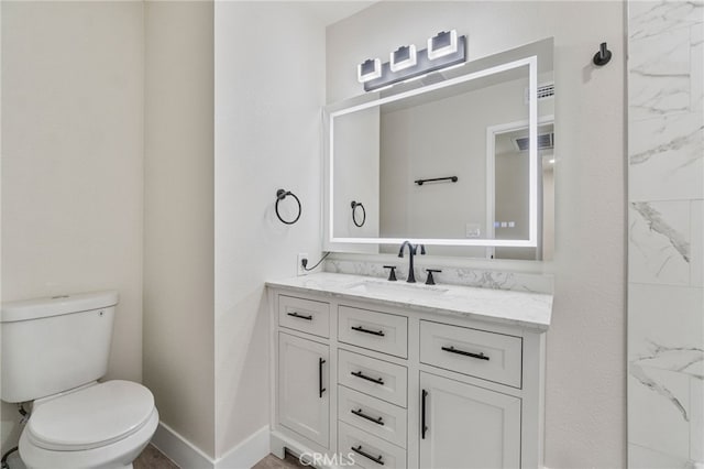bathroom featuring vanity, toilet, and baseboards