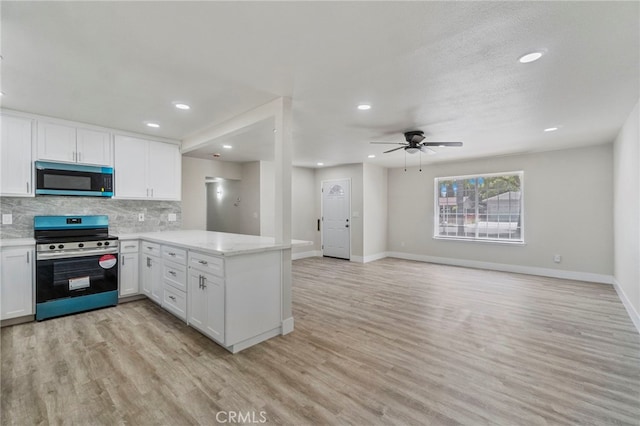 kitchen featuring stainless steel appliances, a peninsula, baseboards, white cabinets, and light wood finished floors