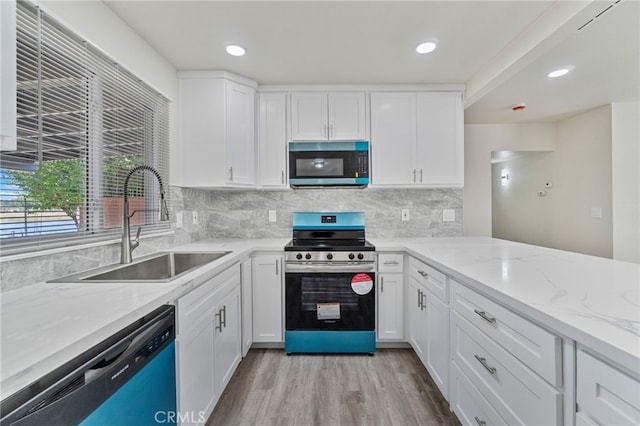 kitchen featuring appliances with stainless steel finishes, a sink, light wood-type flooring, white cabinetry, and recessed lighting