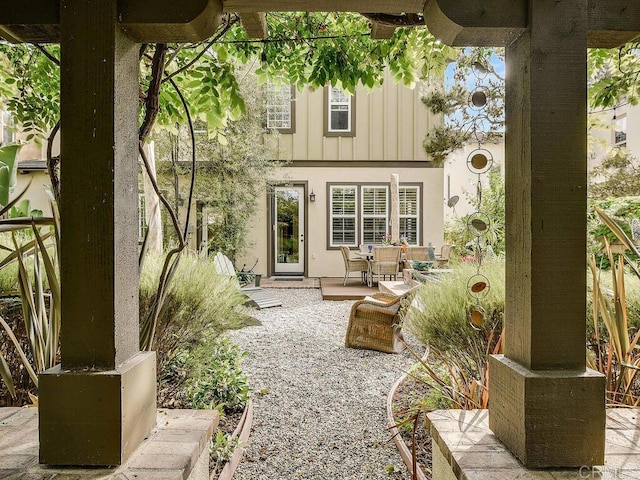 rear view of house featuring board and batten siding, a patio area, and stucco siding