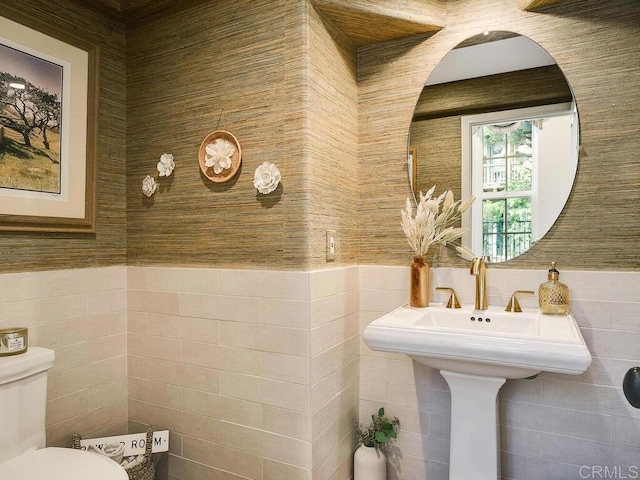bathroom featuring a wainscoted wall, toilet, and tile walls
