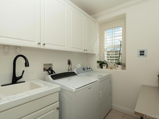 clothes washing area featuring cabinet space, light tile patterned flooring, a sink, ornamental molding, and washing machine and dryer