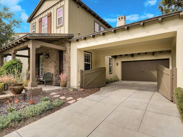 view of front of house featuring board and batten siding, a porch, driveway, a gate, and stucco siding