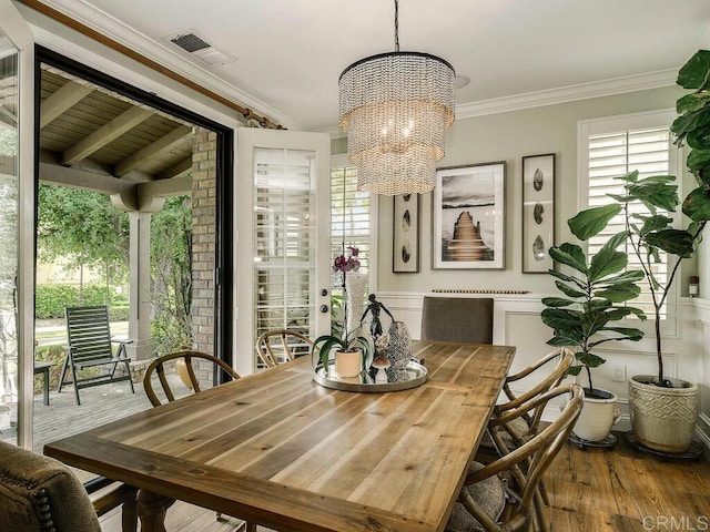 dining room featuring visible vents, crown molding, wood finished floors, and a chandelier