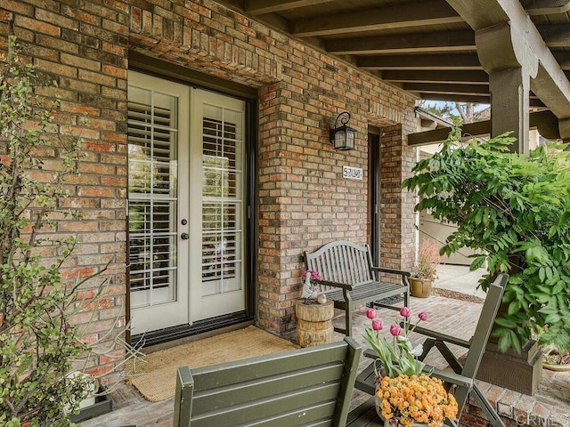 property entrance with brick siding, french doors, and a porch