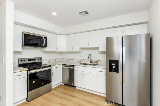 kitchen featuring a sink, white cabinets, light wood-style floors, and stainless steel appliances