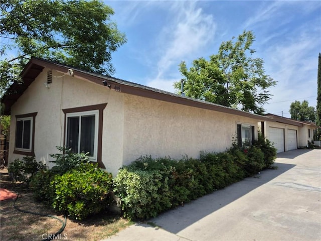 409 E Belmont St, Ontario, CA 91761 - view of side of home featuring stucco siding, concrete driveway, and a garage