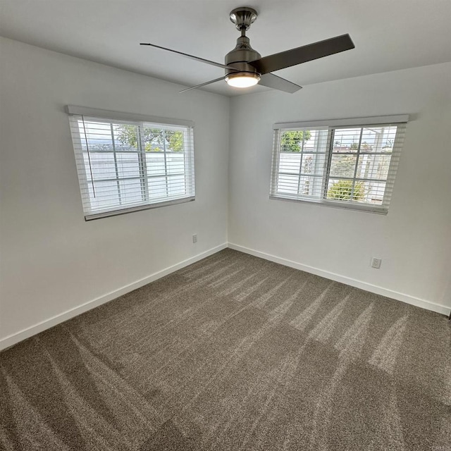 unfurnished room featuring baseboards, dark colored carpet, and a wealth of natural light
