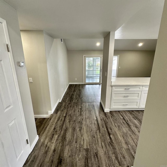 unfurnished room featuring baseboards and dark wood-type flooring