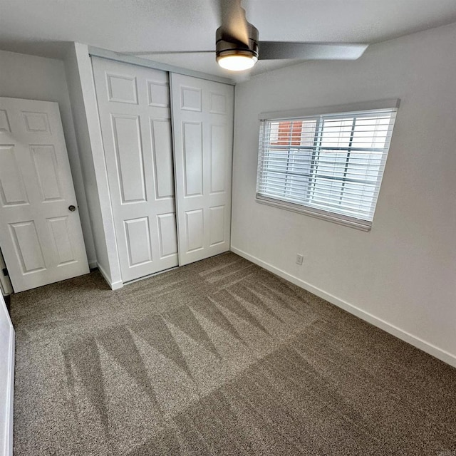 unfurnished bedroom with baseboards, a closet, and dark colored carpet
