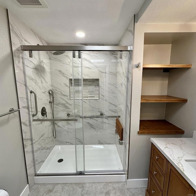 full bath with baseboards, visible vents, a marble finish shower, and vanity
