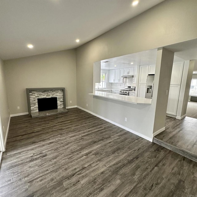 unfurnished living room with plenty of natural light, a fireplace, recessed lighting, and dark wood-type flooring