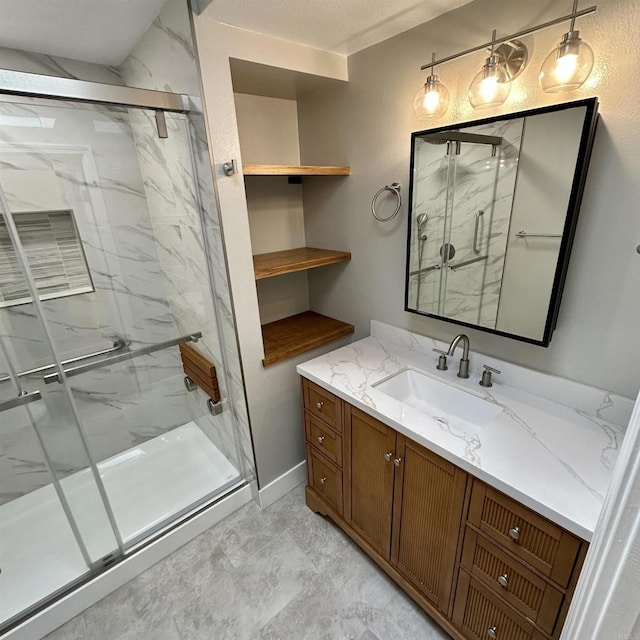 bathroom featuring vanity, a marble finish shower, and baseboards