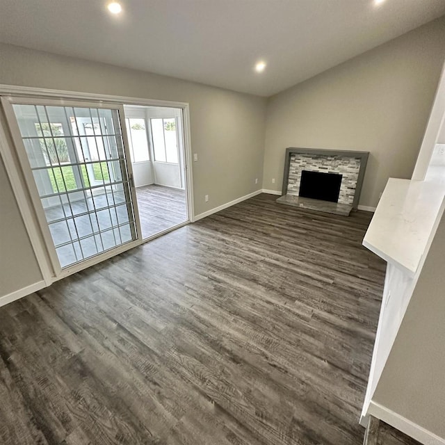 unfurnished living room with recessed lighting, baseboards, a fireplace, and dark wood-style flooring