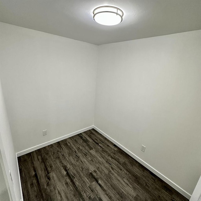 unfurnished room featuring baseboards and dark wood-style flooring