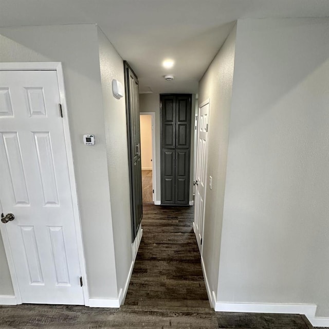 corridor with baseboards and dark wood-style floors