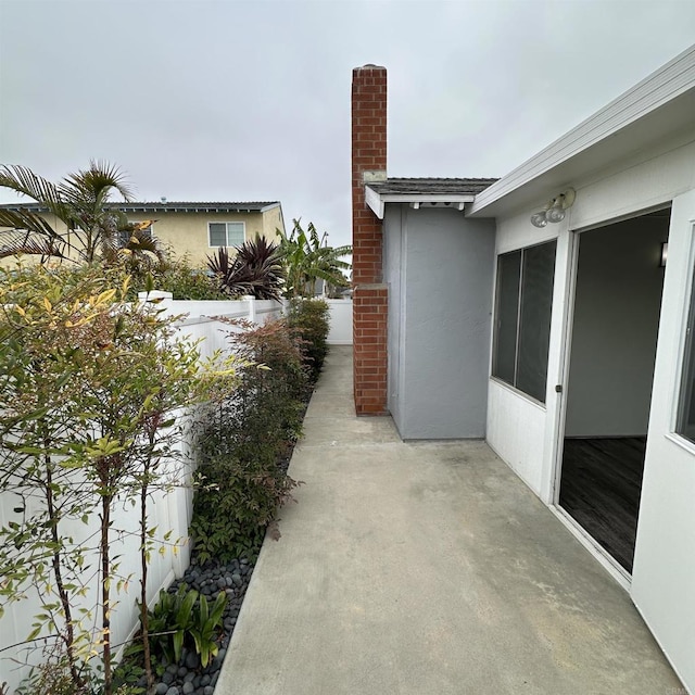 view of home's exterior with fence, a chimney, a patio area, and stucco siding