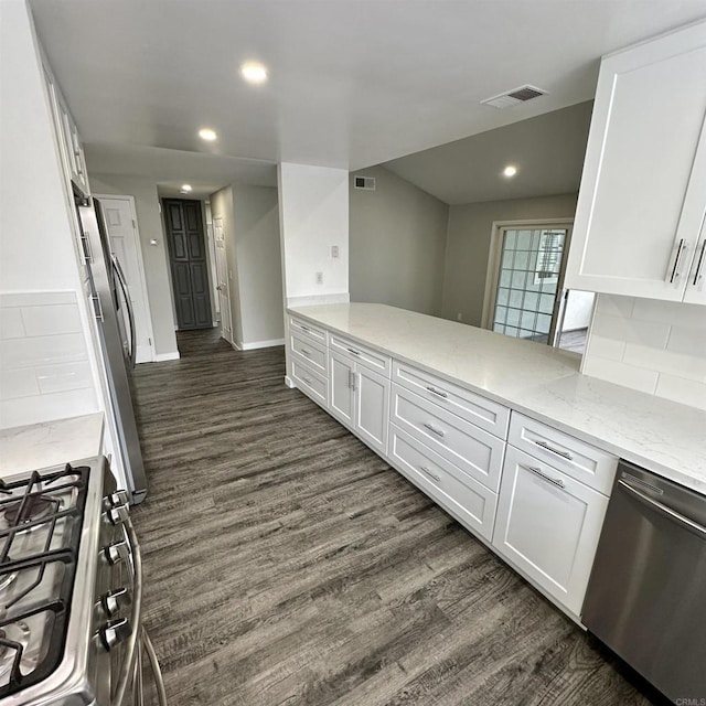 kitchen with white cabinets, stainless steel appliances, visible vents, and dark wood finished floors
