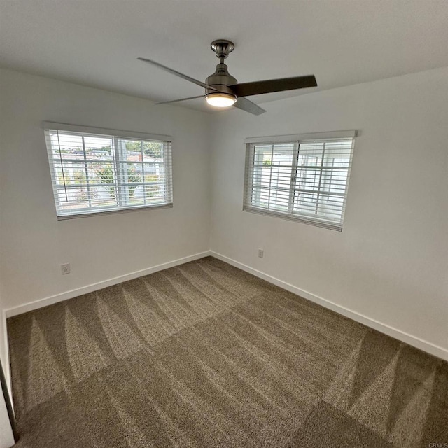 empty room with baseboards, a ceiling fan, and dark colored carpet