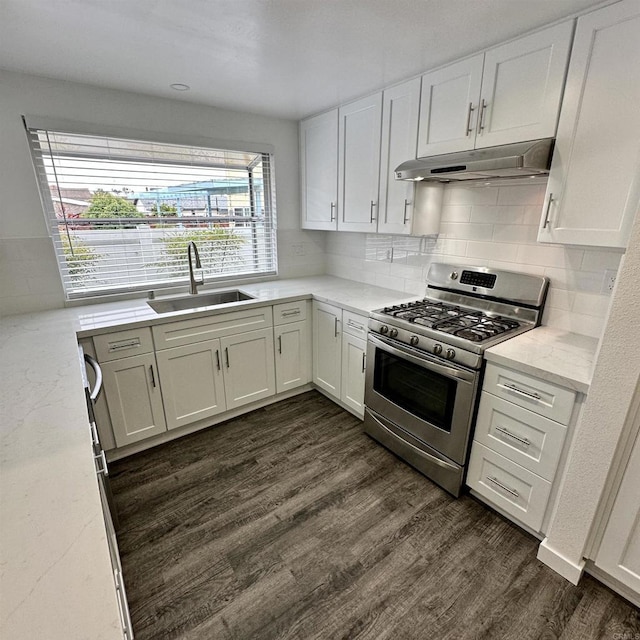 kitchen featuring stainless steel gas range oven, a sink, white cabinets, under cabinet range hood, and dark wood-type flooring