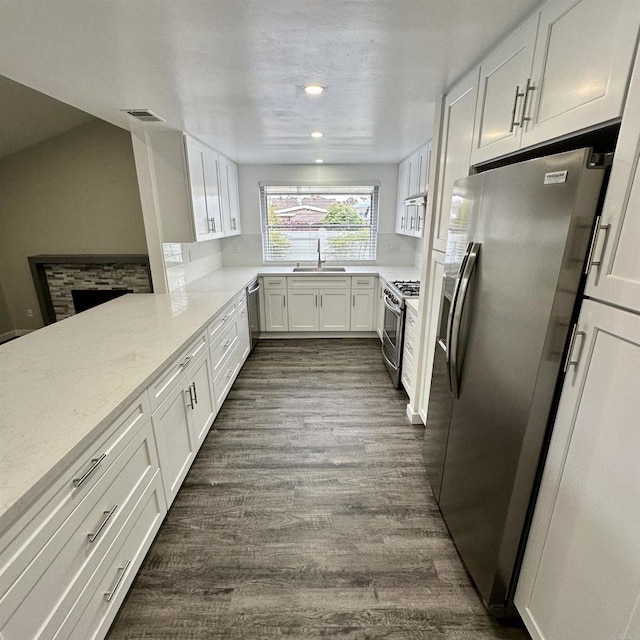 kitchen featuring visible vents, appliances with stainless steel finishes, dark wood finished floors, a sink, and white cabinets