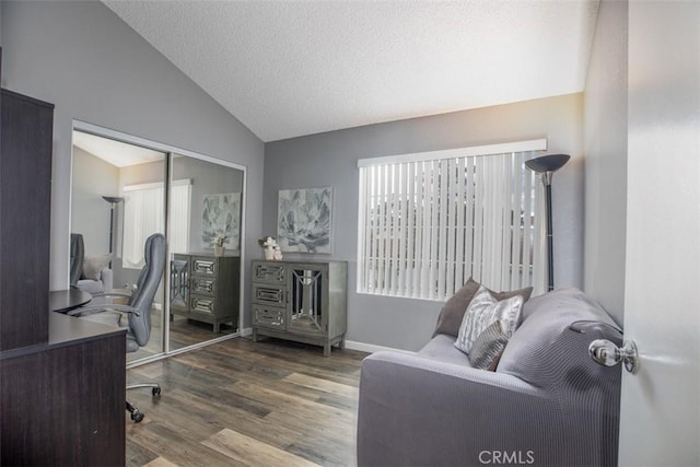 office space featuring baseboards, a textured ceiling, wood finished floors, and vaulted ceiling
