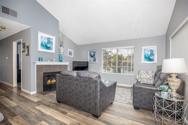 living area featuring baseboards, visible vents, wood finished floors, and lofted ceiling