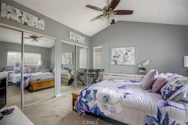 bedroom with carpet floors, ceiling fan, vaulted ceiling, and two closets