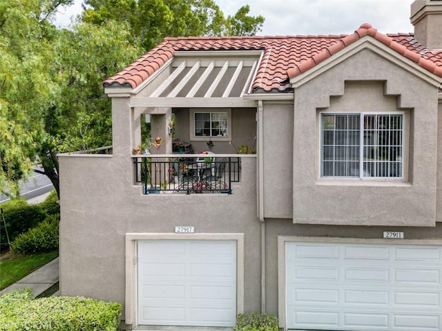 view of front of home with an attached garage, a tile roof, and stucco siding