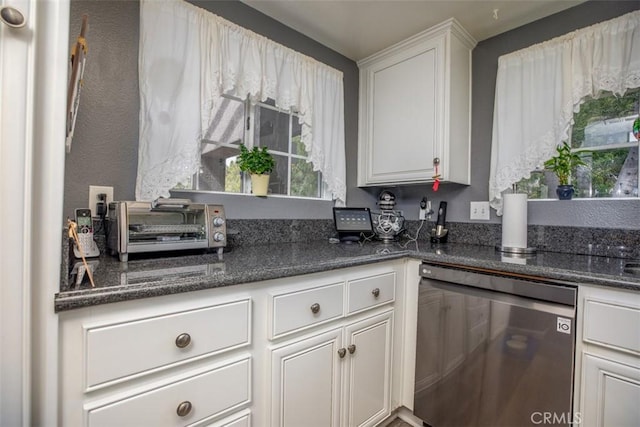 kitchen featuring a toaster, dark stone counters, white cabinets, and stainless steel dishwasher