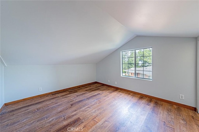 bonus room featuring baseboards, vaulted ceiling, and wood finished floors