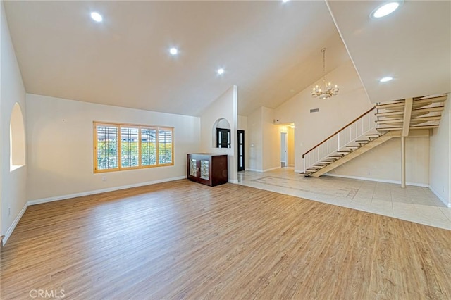 unfurnished living room with baseboards, high vaulted ceiling, stairway, and light wood-type flooring