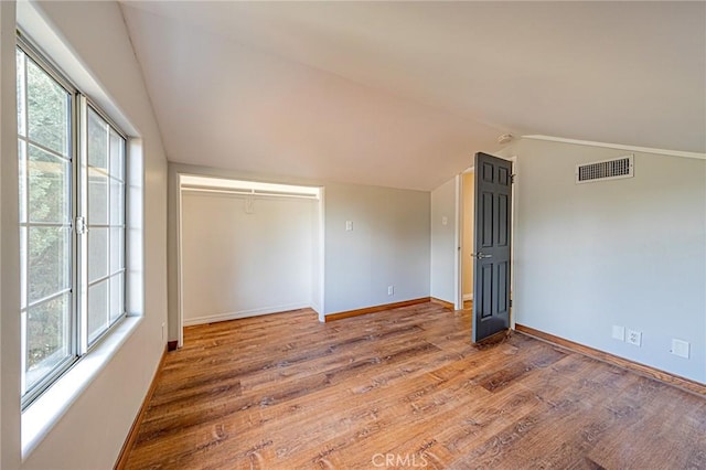 empty room with baseboards, visible vents, wood finished floors, and lofted ceiling