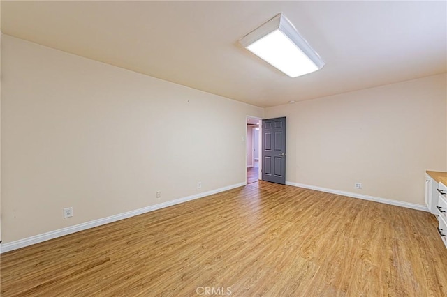spare room featuring light wood-style floors and baseboards
