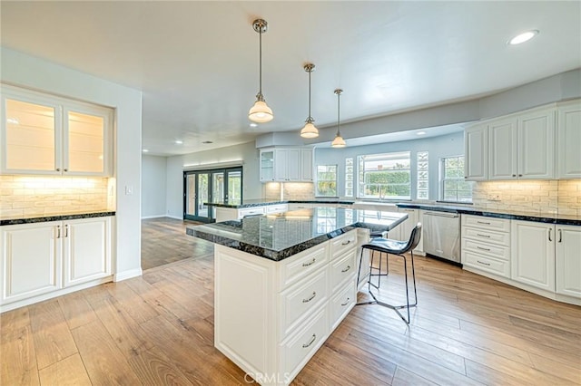 kitchen featuring stainless steel dishwasher, decorative backsplash, and light wood-style flooring